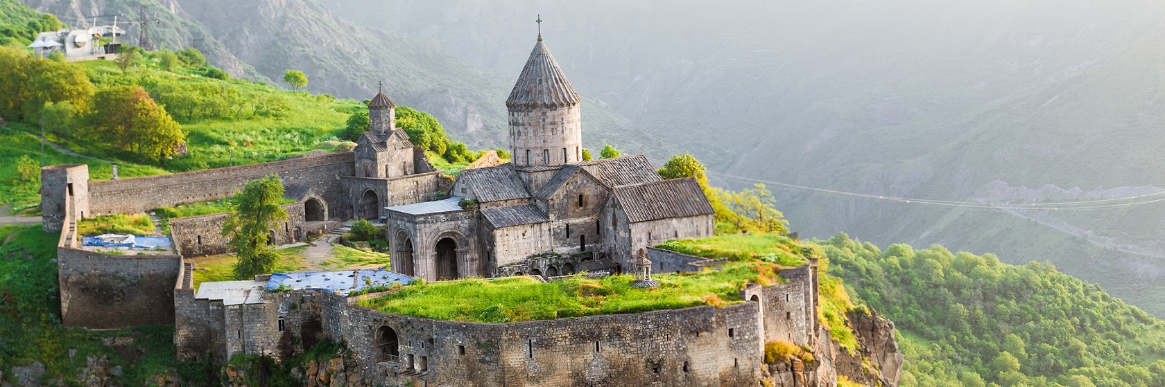 Tatevklostret i Armenien, som ligger p� ett klipputspr�ng med branta bergssidor, dalen nedanf�r �r fylld av ljusgr�na l�vtr�d.