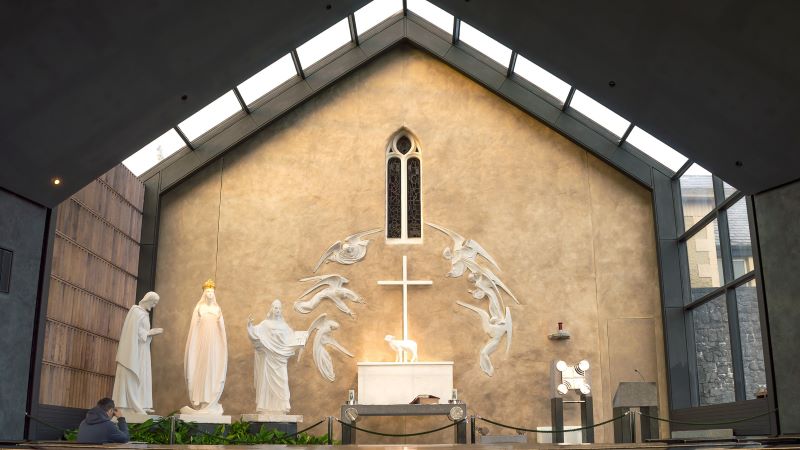 Knock-kapellet p� Irland, med tre vita statyer och en v�ggfresk med sex �nglar, mot en beigekalkad v�gg.